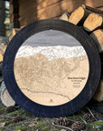 Matte Onyx Breckenridge ski trail map cribbage board displayed beside stacked firewood