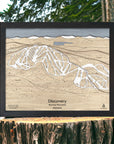 3D wooden ski resort map of Discovery Ski Area on a wooden stump.