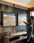 Man and woman pointing at wooden map of Eldora Ski Resort and admiring their skiing wall art.