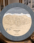 Graphite Grey Jackson Hole ski map cribbage board staged on a cabin table with playing cards and après-ski snacks.