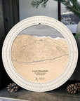 Arctic White Loon Mountain ski map cribbage board displayed with pinecones and greenery on a rustic shelf in a ski cabin.