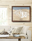 Framed map of Pats Peak ski resort on a wall above a sofa in a cozy ski cabin.