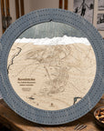 Graphite Grey Revelstoke ski map cribbage board staged on a wooden table inside a rustic mountain cabin.