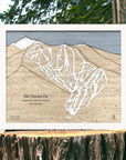 Wooden trail map of Ski Santa Fe on a tree stump with a natural background
