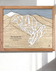 3D Wooden framed trail map of Ski Santa Fe on a white wall inside a modern ski house.