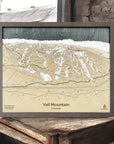 Framed topographic map of Vail Mountain, Colorado on a wooden surface.