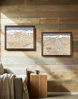 Framed Whistler Blackcomb ski map above a seated skier holding a mug in a quiet, rustic mountain cabin