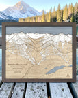 Graphite-framed Whistler Blackcomb wood ski map displayed on a deck overlooking an alpine lake and mountains