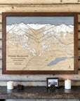 Rustic Mocha-framed Whistler Blackcomb wood ski map on a light cabin wall above candles, pinecones and a small photograph.