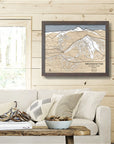 Framed wooden map of Yellowstone Club Ski Resort on a wooden wall above a sofa in a cozy ski cabin.