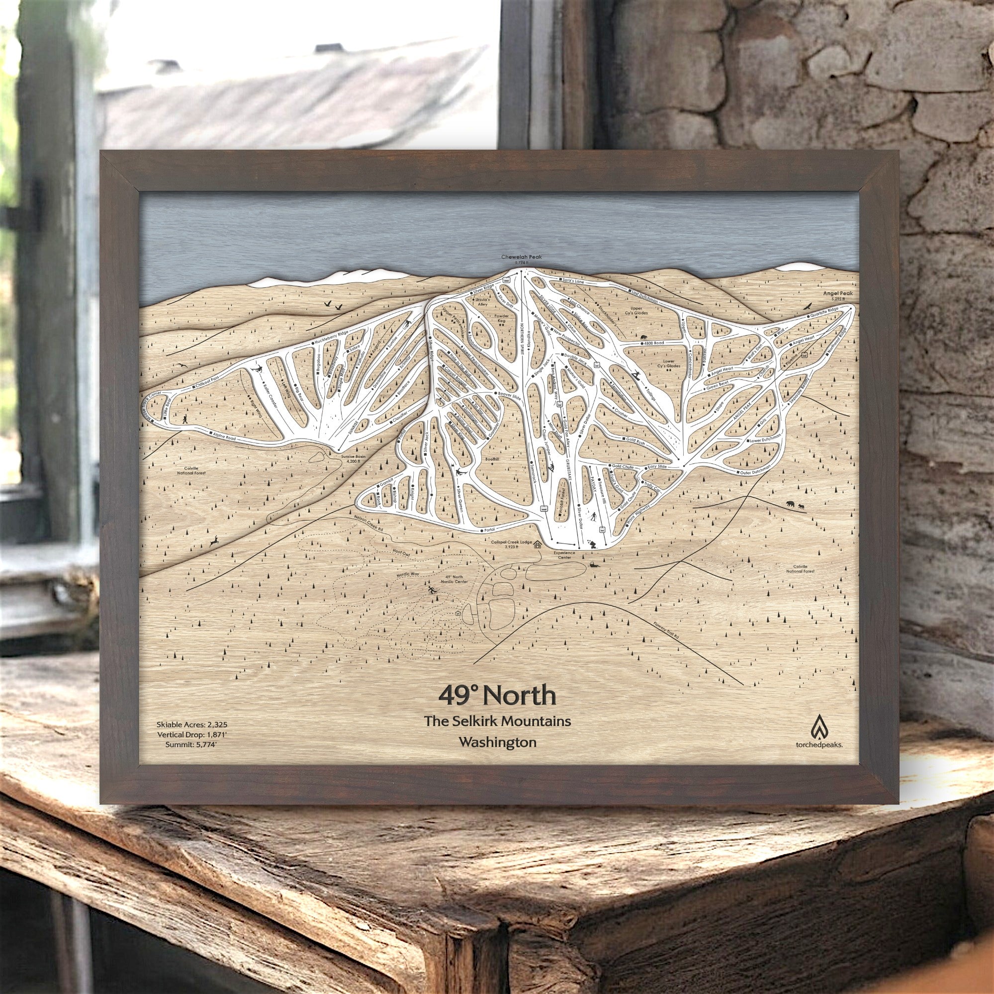 Wooden map of 49° North Ski Resort in Washington on a rustic wooden surface inside a ski cabin. 