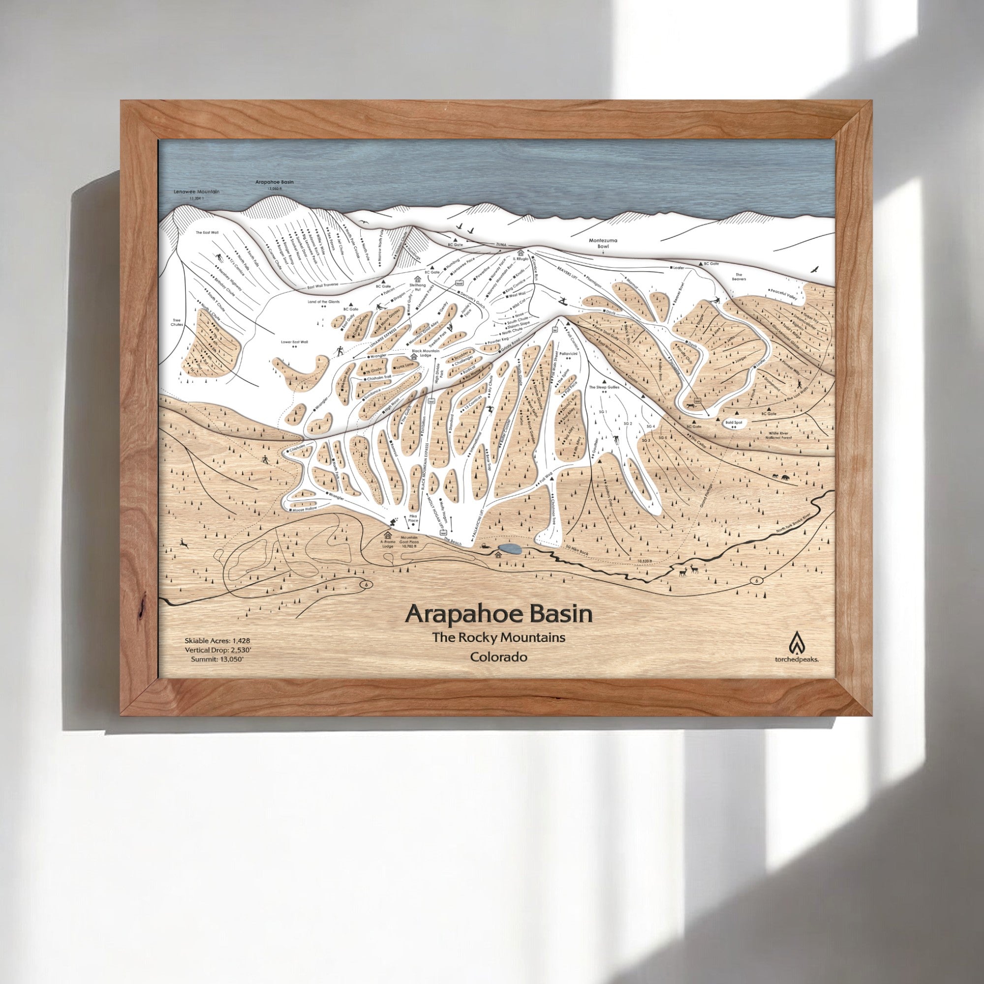 Wooden framed map of Arapahoe Basin Ski Resort in The Rocky Mountains, Colorado on a white wall.