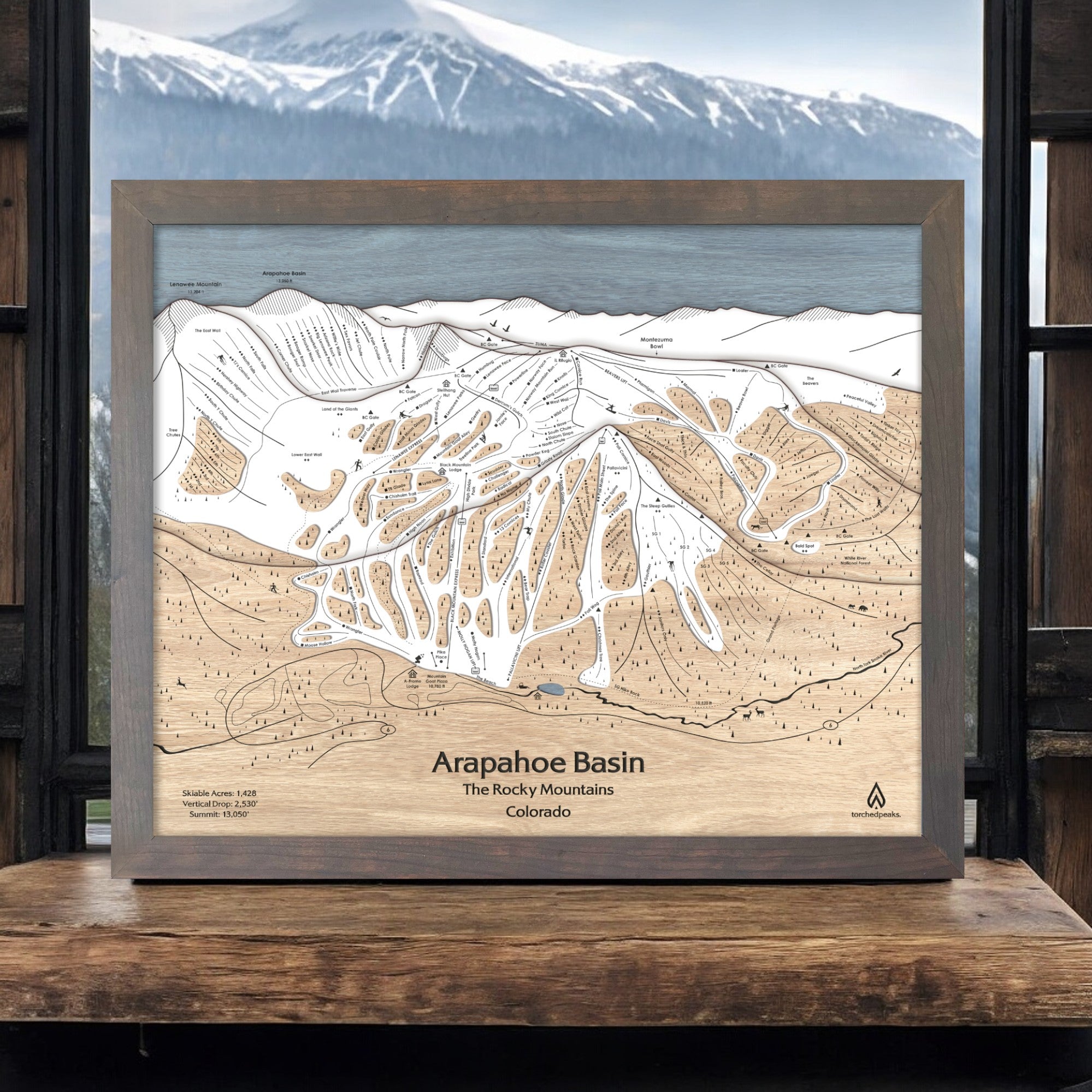 Wooden map of Arapahoe Basin Ski Resort with a mountainous background