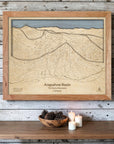 Natural Arapahoe Basin wooden ski map mounted on a whitewashed plank wall above candles and pinecones as ski cabin décor.