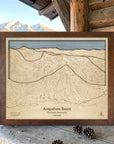 Rustic Mocha Arapahoe Basin framed ski map displayed on a cabin porch with snowy mountains in the background, a unique gift for skiers.