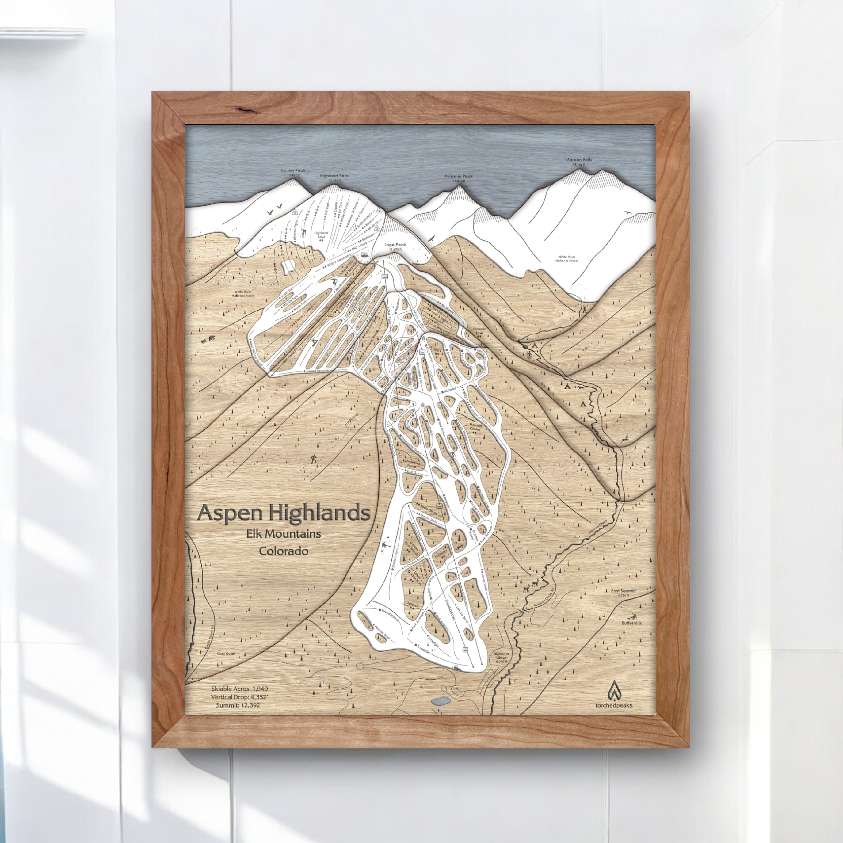 Framed map of Aspen Highlands on a white wall. Wooden ski resort map, laser engraved. 
