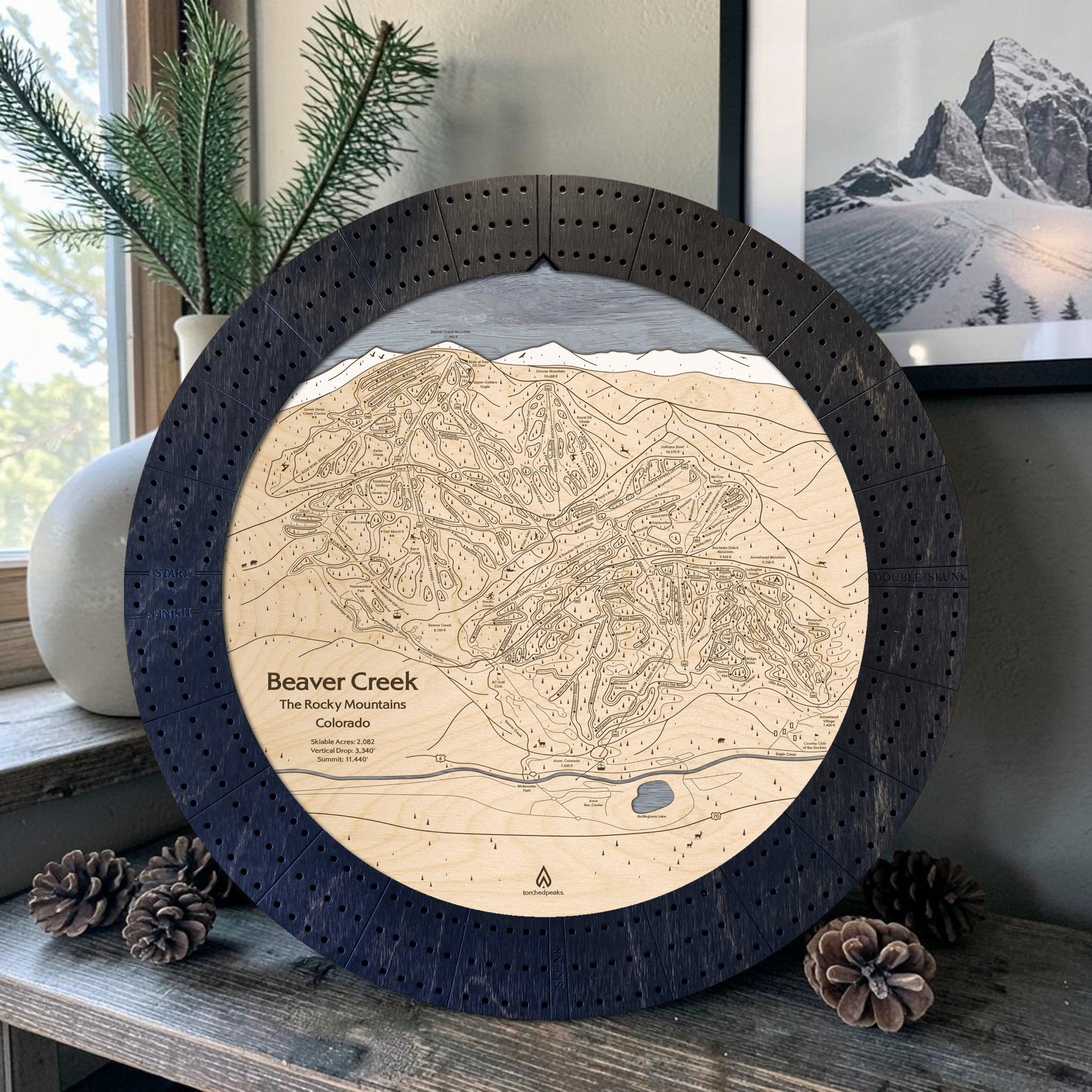 Matte Onyx Beaver Creek ski map cribbage board displayed with pinecones as modern ski cabin décor.