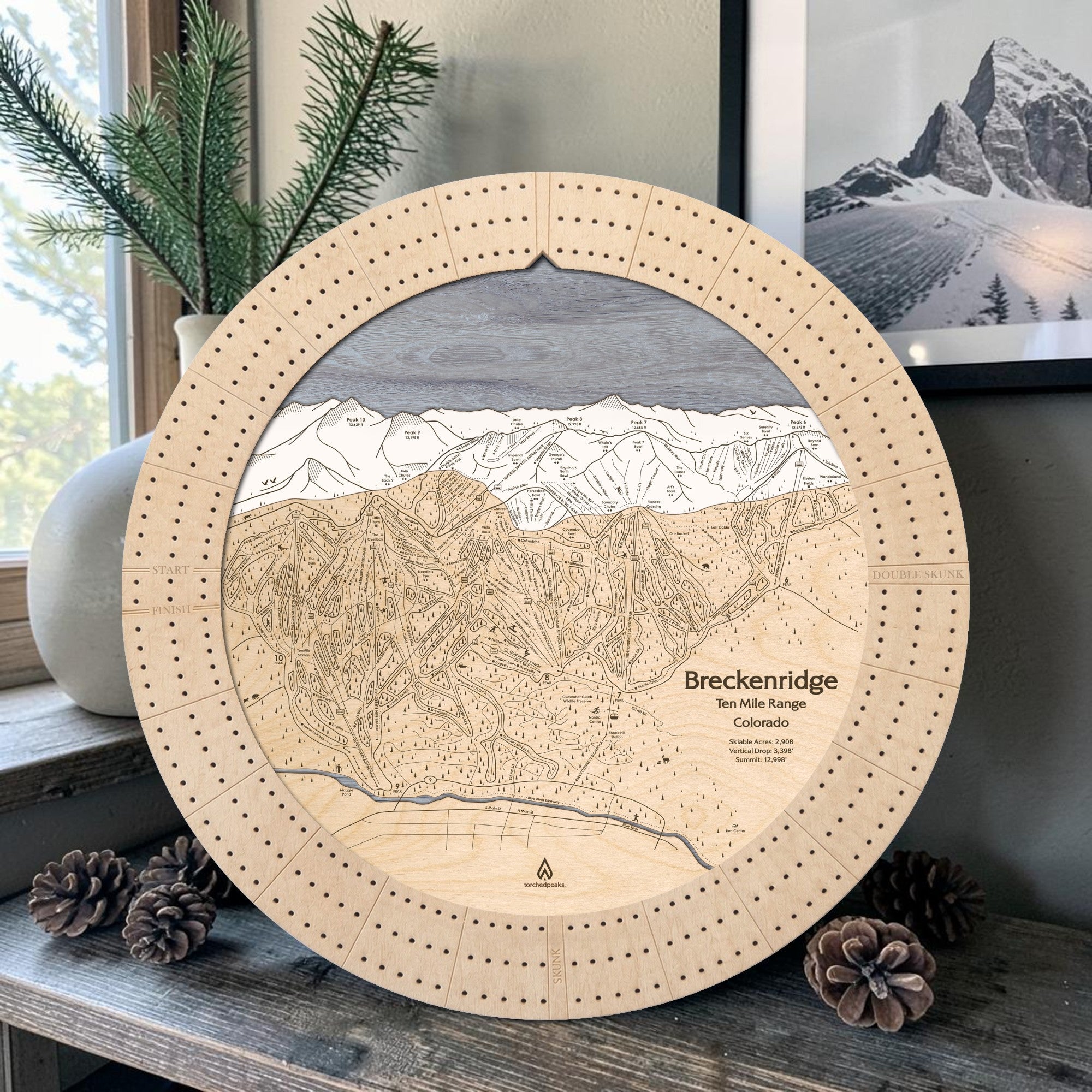 Birch Breckenridge wooden ski map cribbage board displayed with pinecones and greenery as ski cabin décor
