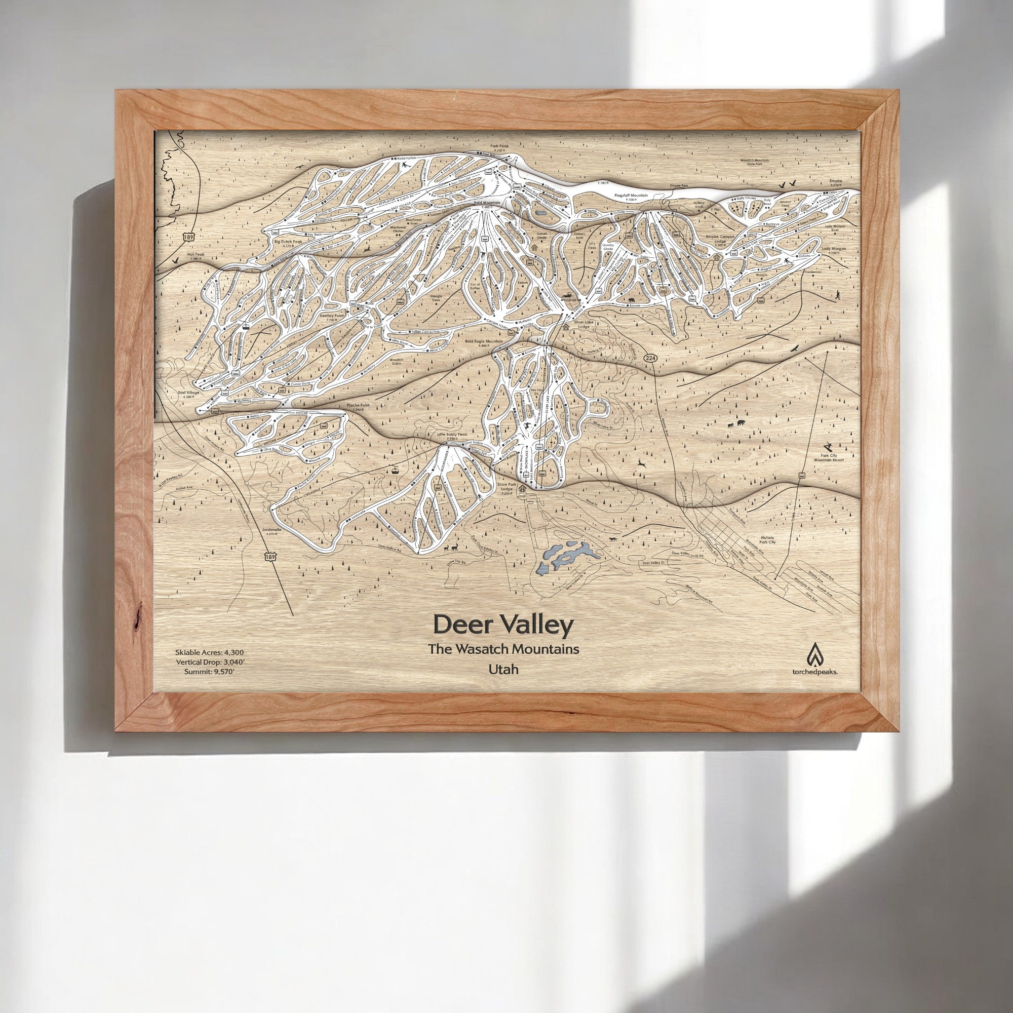 Wooden framed map of Deer Valley Ski Trails in the Wasatch Mountains on a white wall.