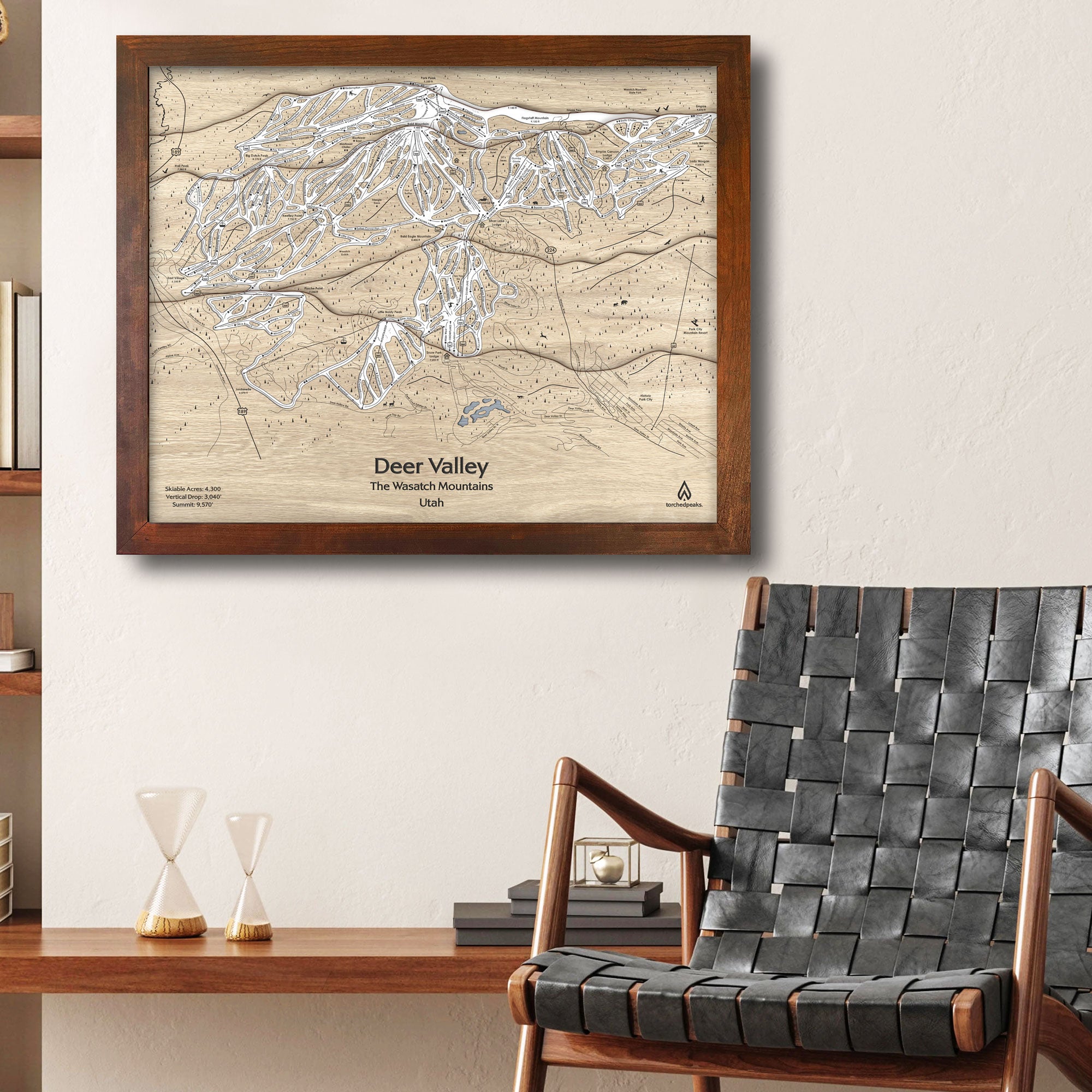 Framed wooden map of Deer Valley Ski Resort on a wall above a chair in a ski cabin.
