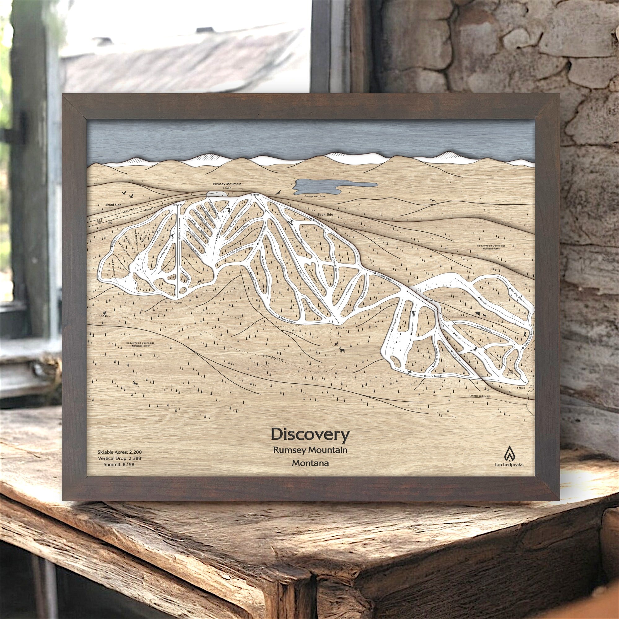 Wooden trail map of Discovery Ski Area on a rustic wooden surface inside a cozy ski cabin. 
