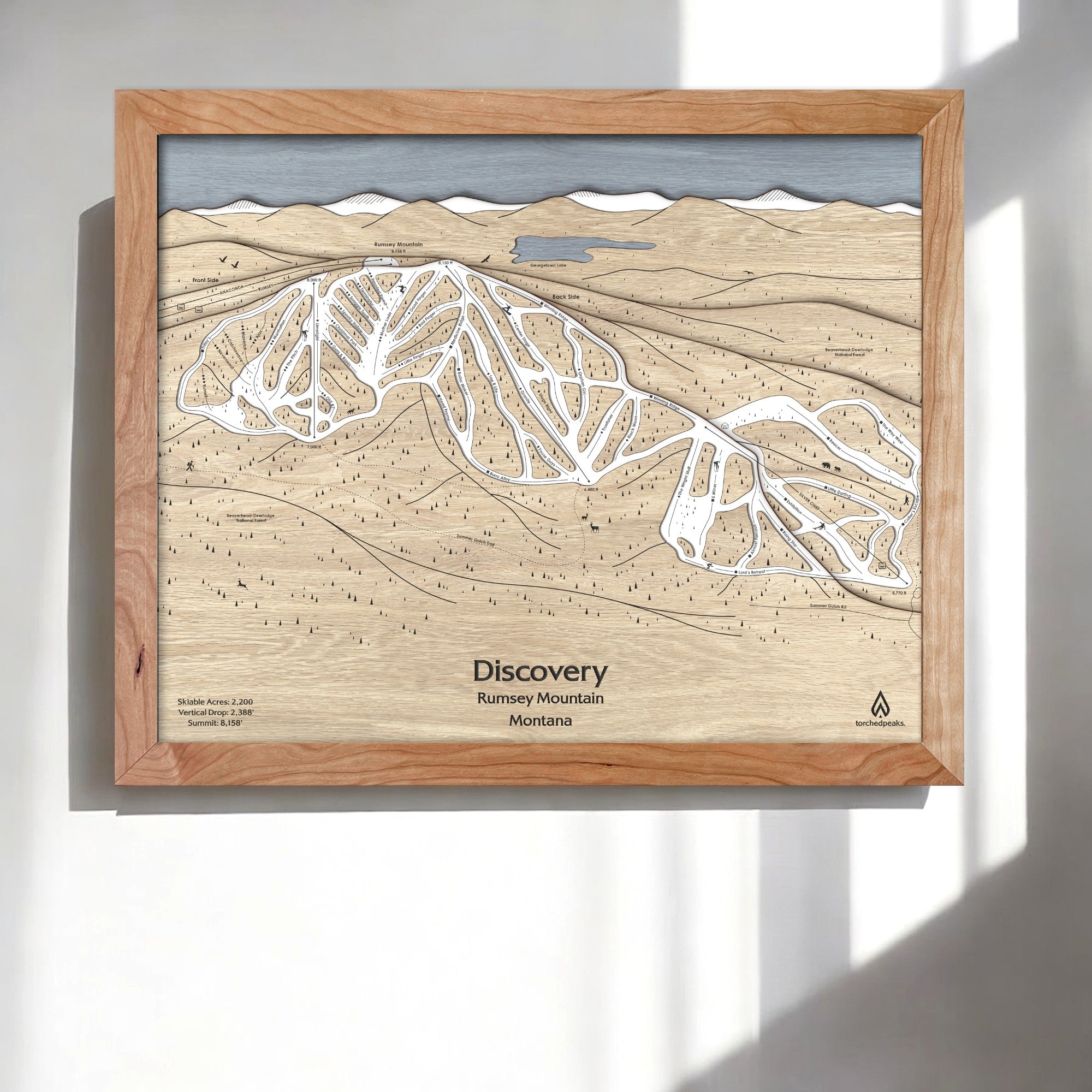 Wooden framed skiing map of  Discovery Ski Area on a white wall in a modern ski house. 
