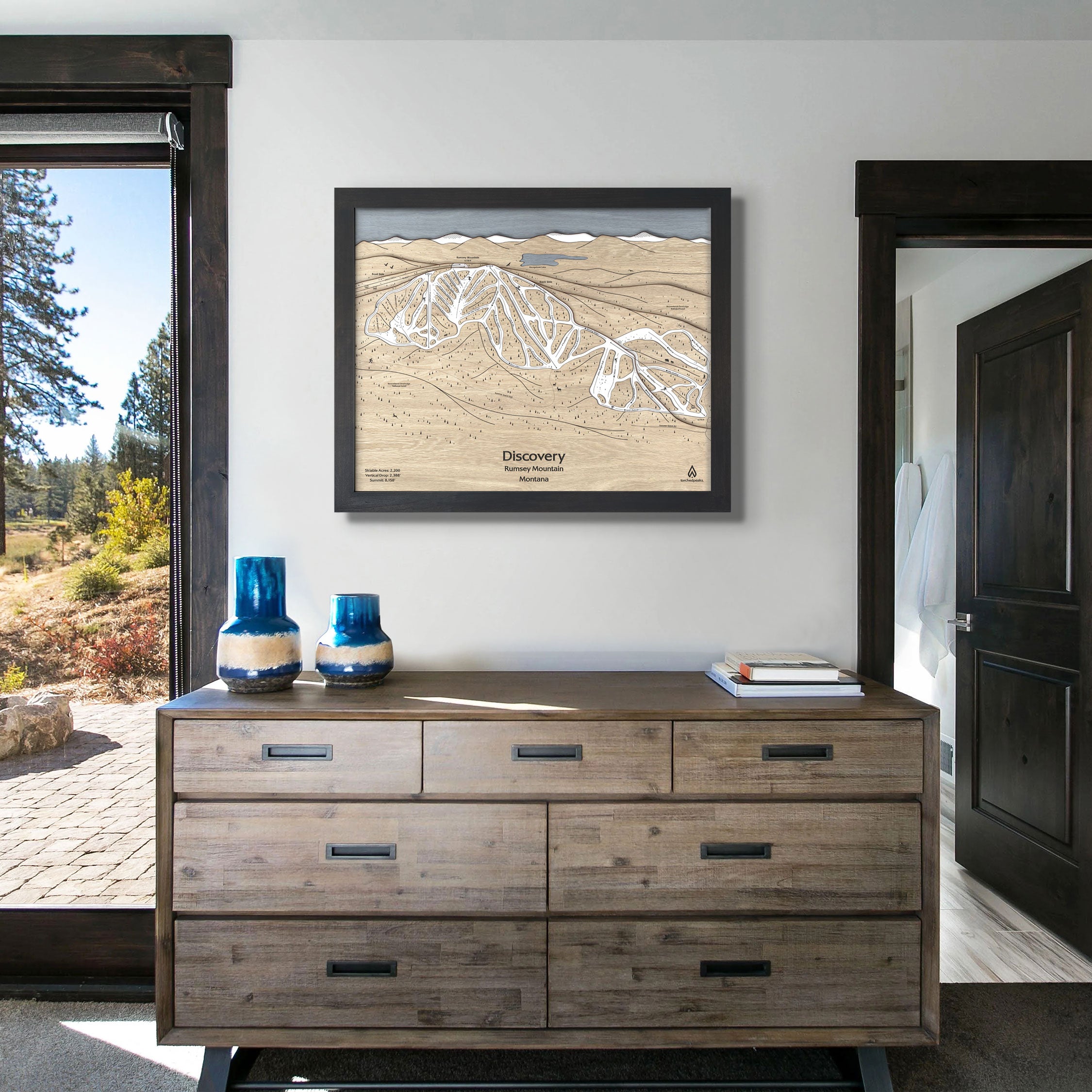 framed artwork of Discovery Ski Area above a dresser inside a modern ski cabin. 