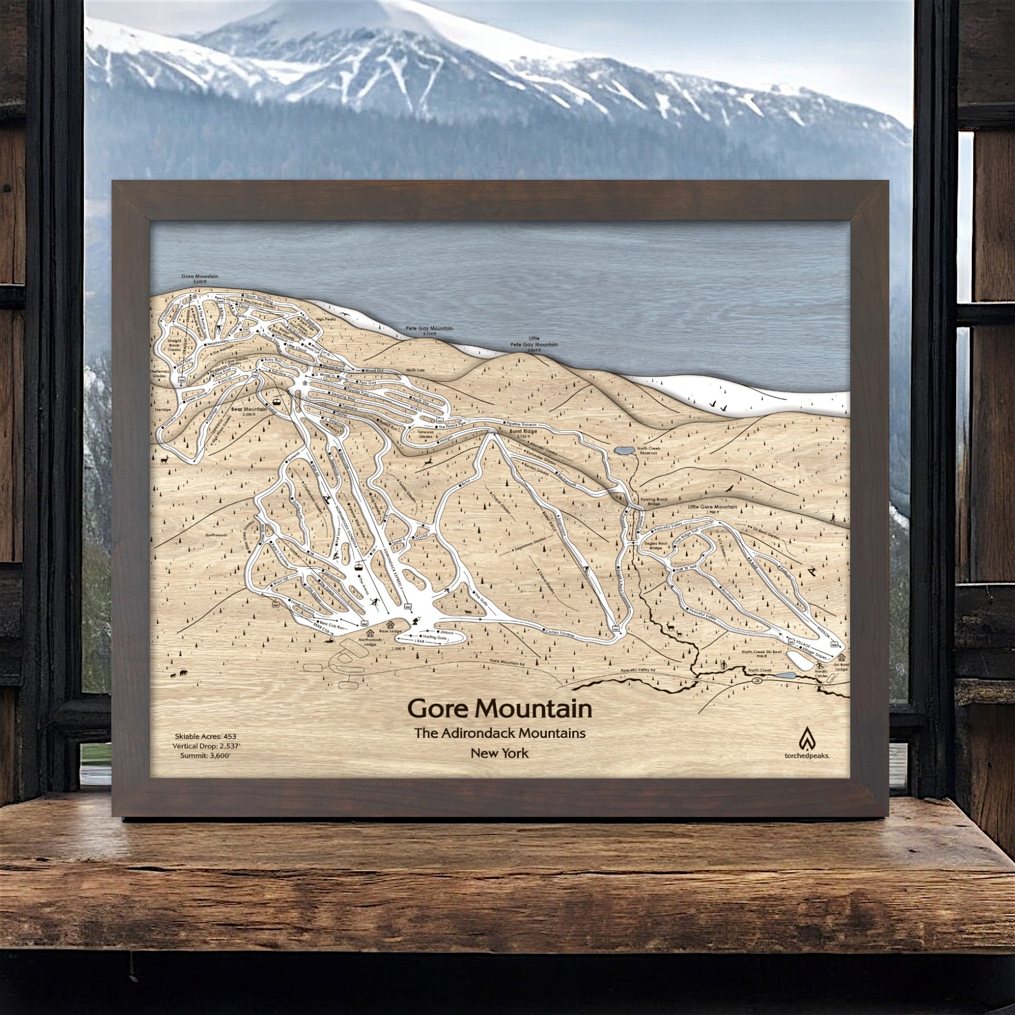 Framed wooden map of Gore Mountain ski resort with mountain view in the background