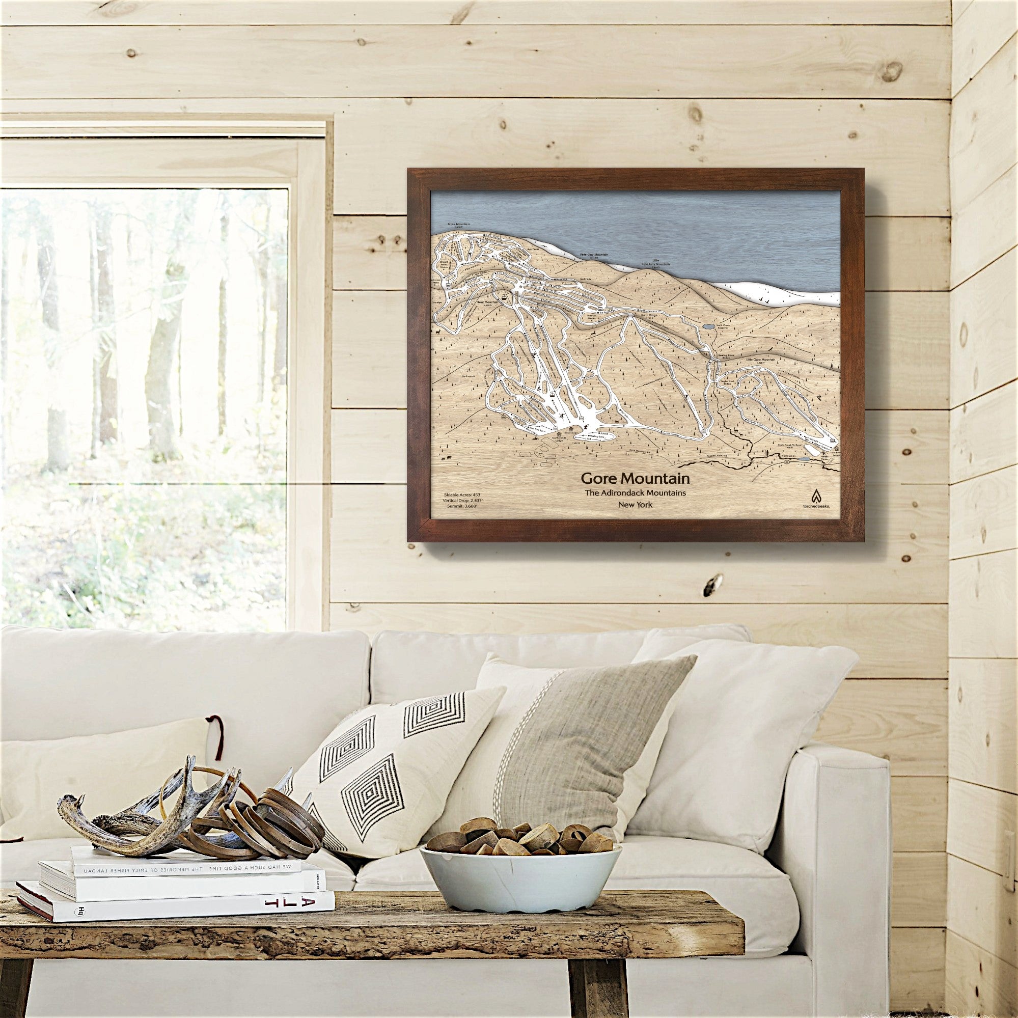 Framed map of Gore Mountain on a wall in a living room with a couch and decor.