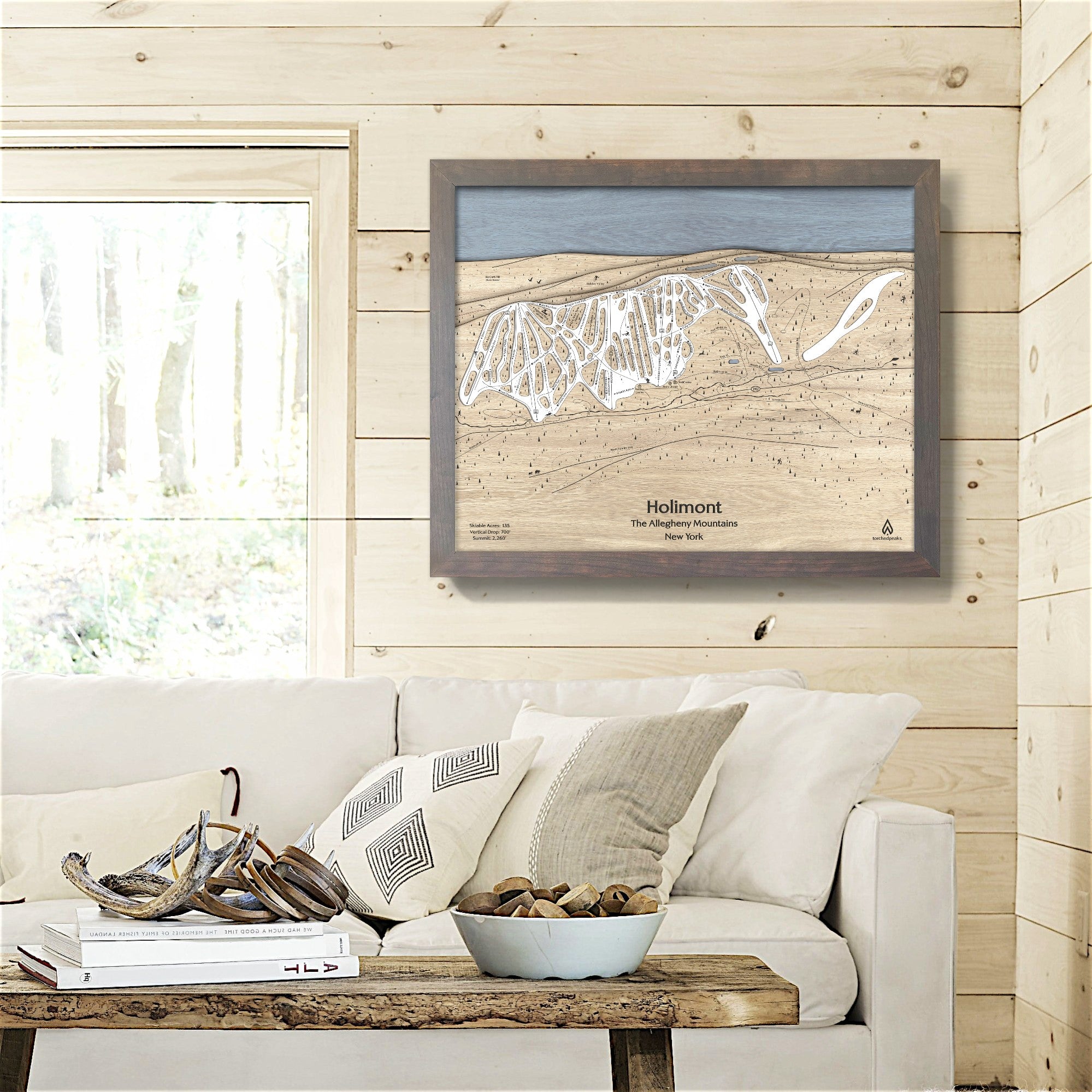 Framed topographic map of Holimont Ski Resort on a wall in a living room inside a rustic ski cabin.