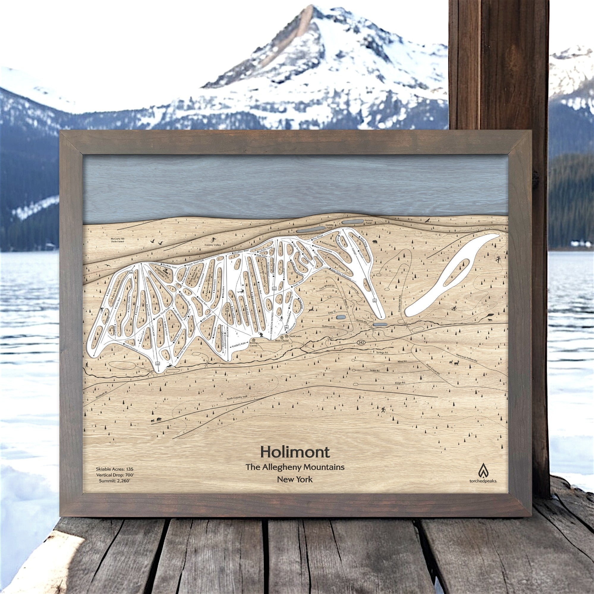 Wooden trail map of Holimont Ski Slopes, The Allegheny Mountains, New York, framed against a scenic mountain backdrop.