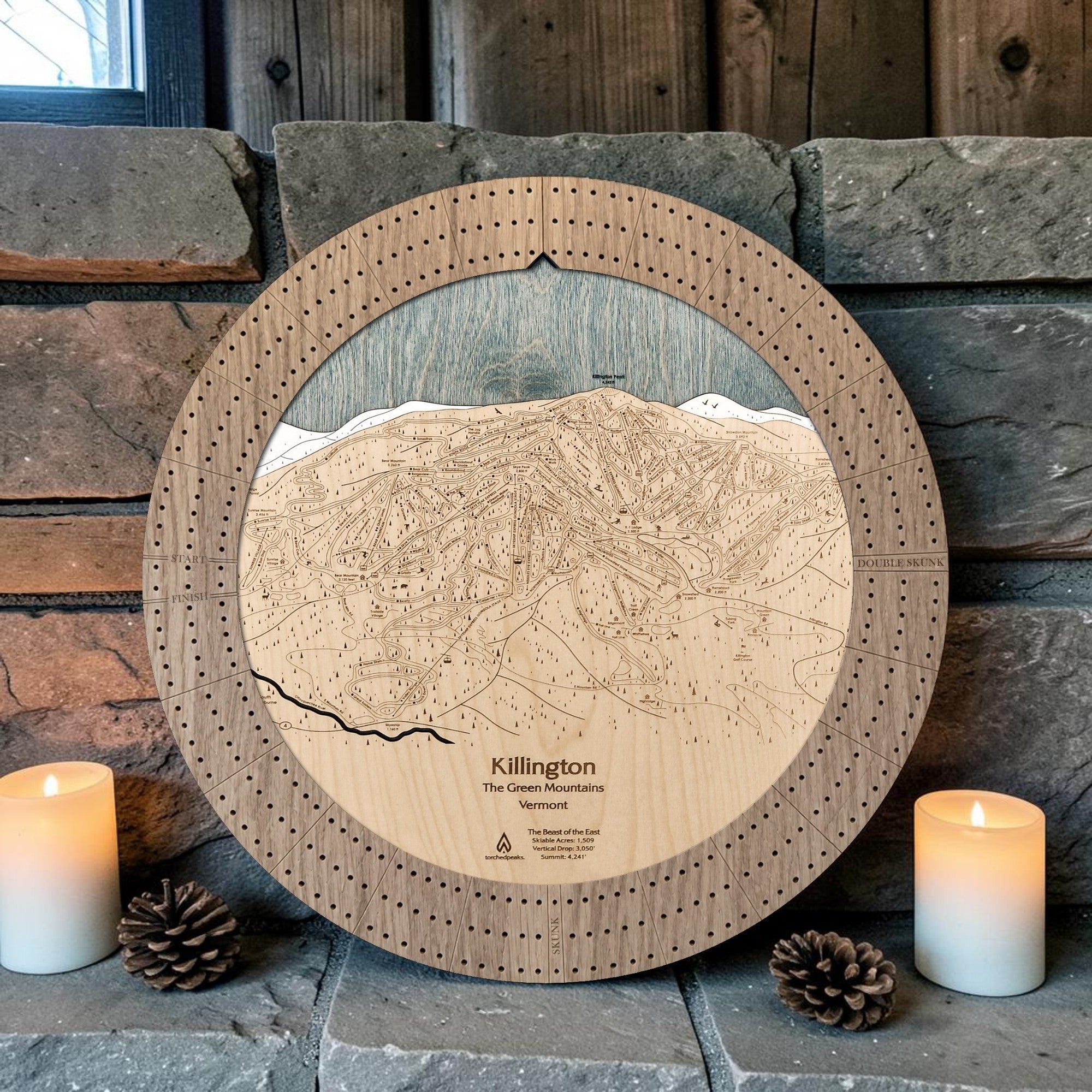 Killington cribbage board in Weathered Timber beside a stone fireplace with candles and pinecones
