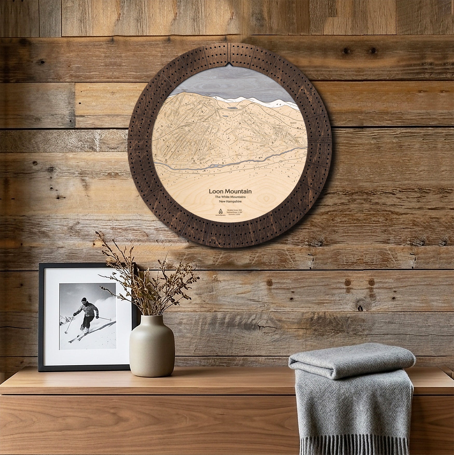 Loon Mountain wooden ski map cribbage board mounted on a reclaimed-wood wall above a console as functional ski cabin wall art.
