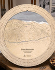 Birch Loon Mountain ski trail map cribbage board displayed on a wooden table beside playing cards and snacks. Example of apres ski board game. 