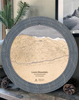 Graphite Grey Loon Mountain wooden cribbage board displayed with pinecones and a framed mountain photograph in a modern ski condo. 