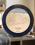 Matte Onyx Loon Mountain ski map cribbage board displayed beside books and a gray blanket as ski cabin décor.