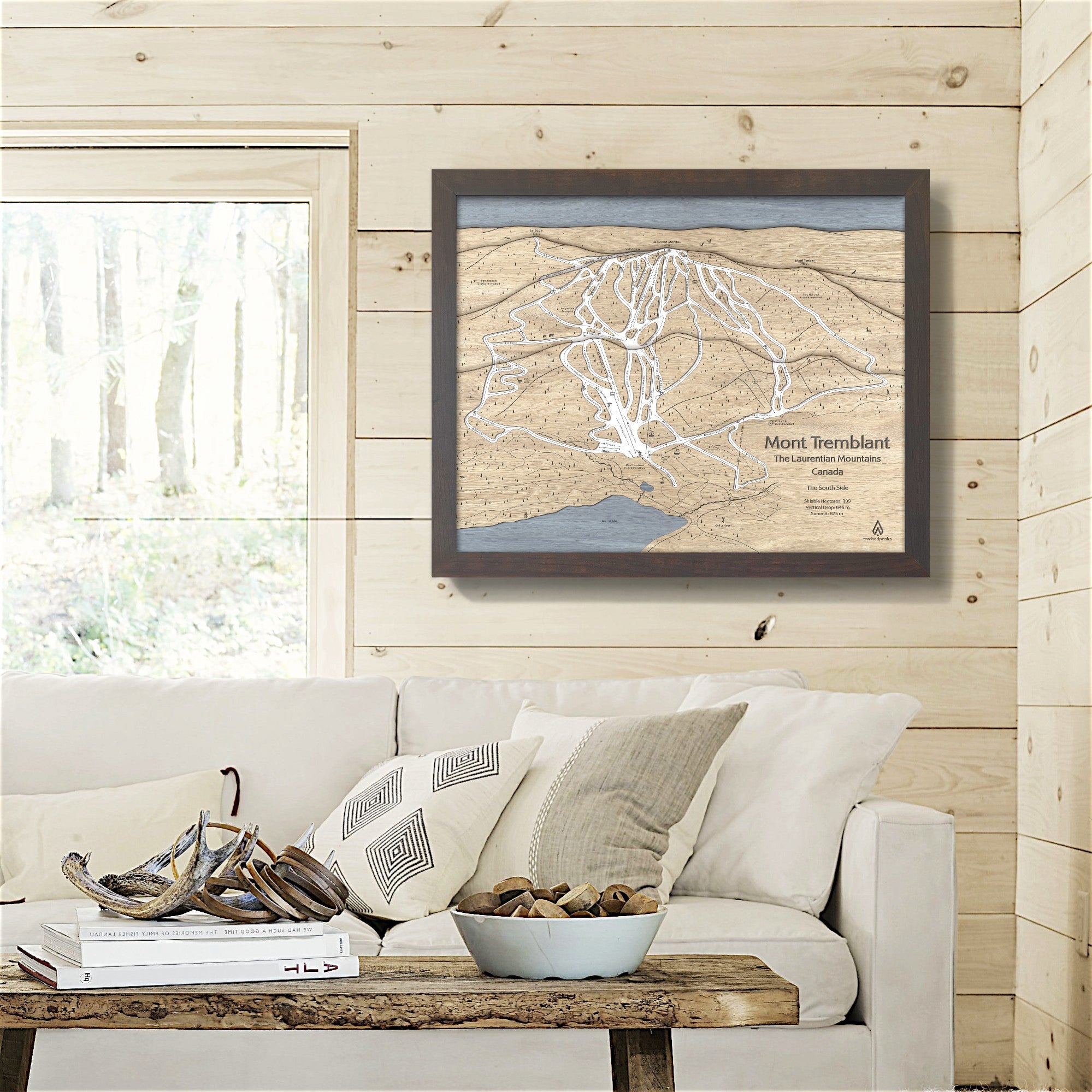 Framed 3D wood map of Mont Tremblant on a wooden wall above a sofa in a ski cabin
