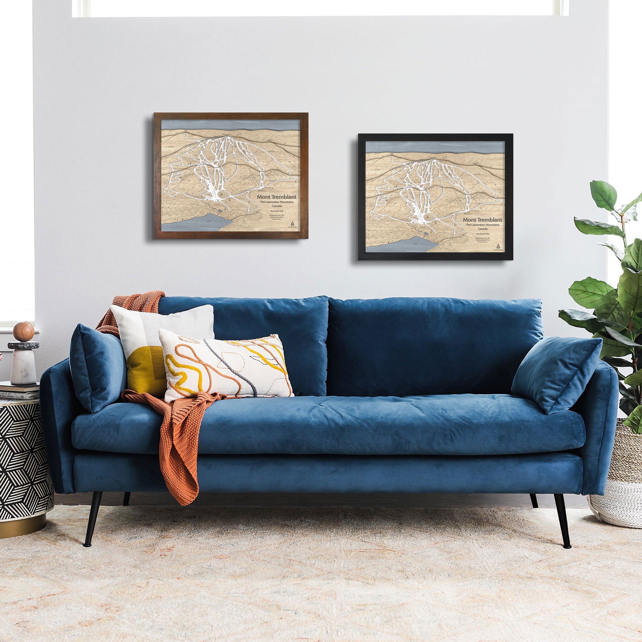 Framed ski maps of Mont Tremblant above a blue sofa in a ski cabin. 