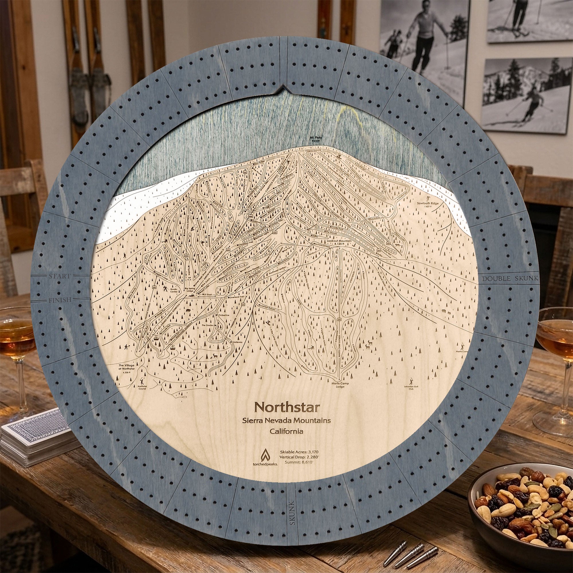 Northstar wooden ski trail map cribbage board in Graphite Grey on a rustic cabin table.