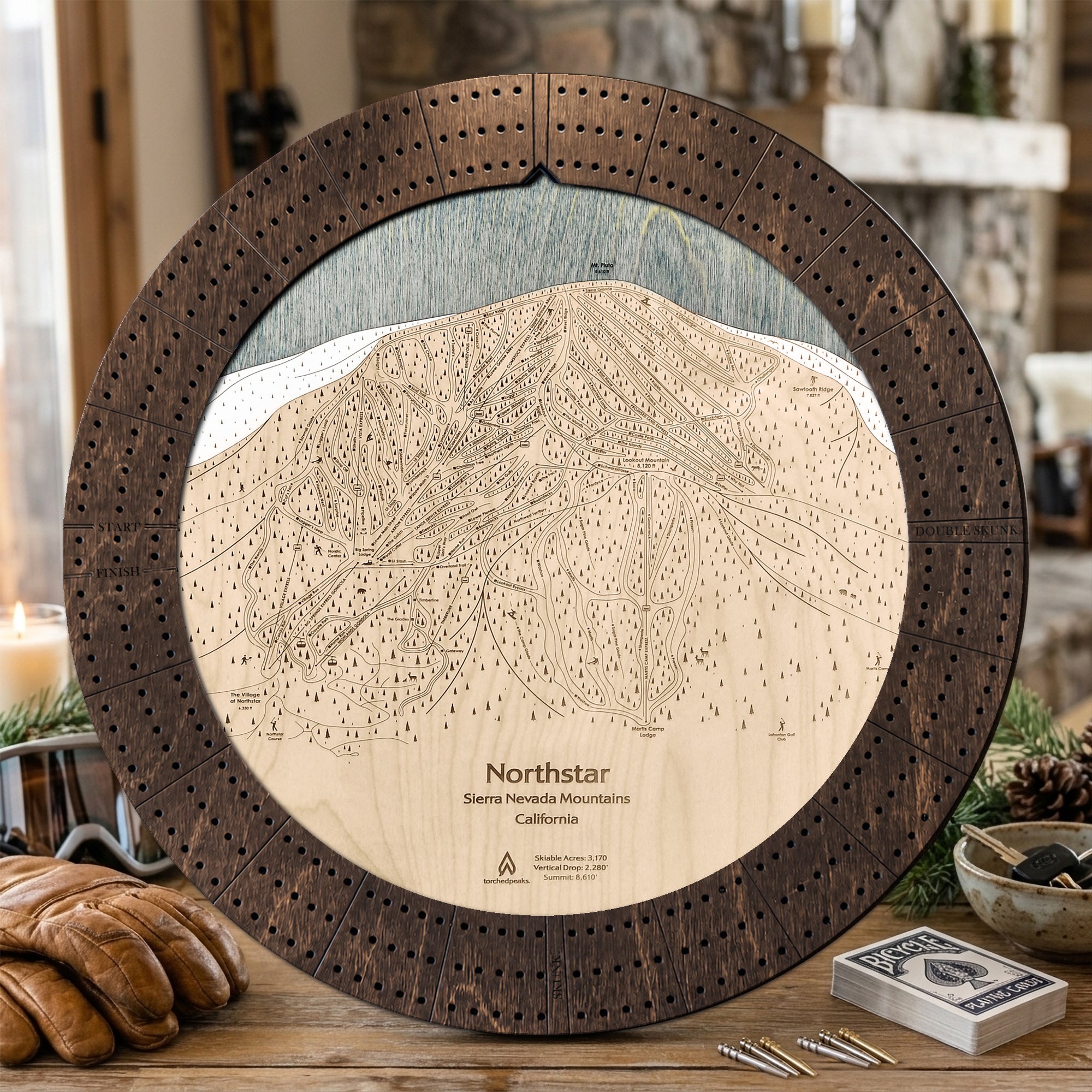 Northstar wooden ski trail map cribbage board in Rustic Mocha styled on a cabin table.