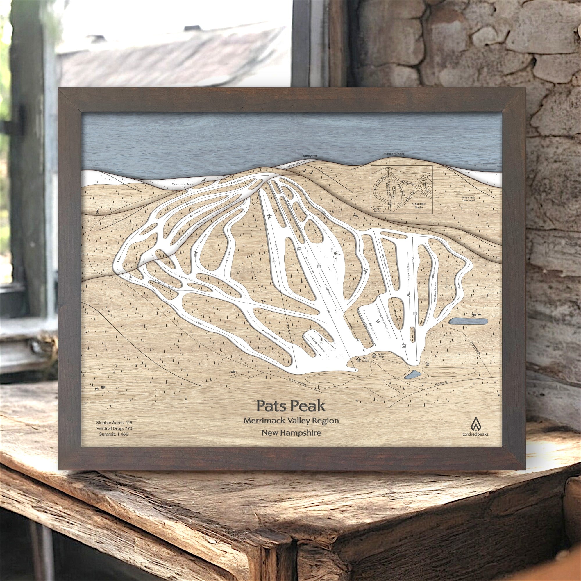 Framed 3d wood map of Pats Peak ski resort on a wooden surface in a rustic ski cabin. 