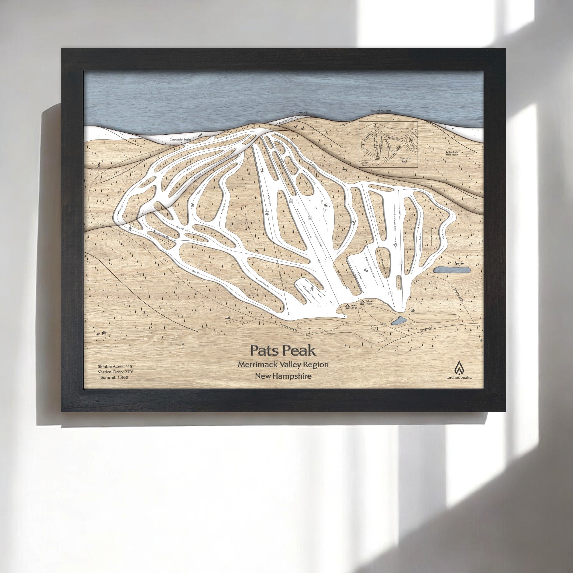 Framed 3D layered wood map of Pats Peak Ski Resort on a white wall in a modern ski house. 
