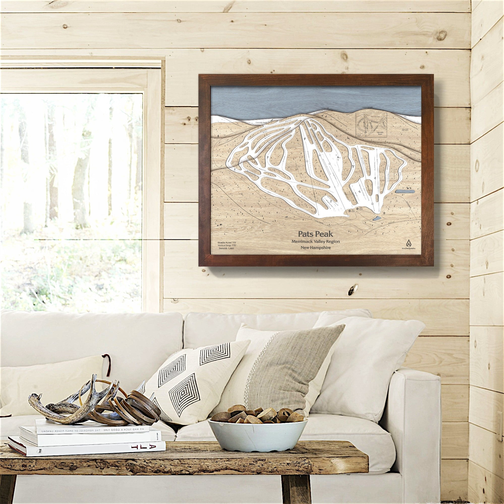 Framed map of Pats Peak ski resort on a wall above a sofa in a cozy ski cabin.