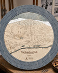 Graphite Grey Quechee Club wooden ski map cribbage board staged on a table inside a rustic ski cabin.