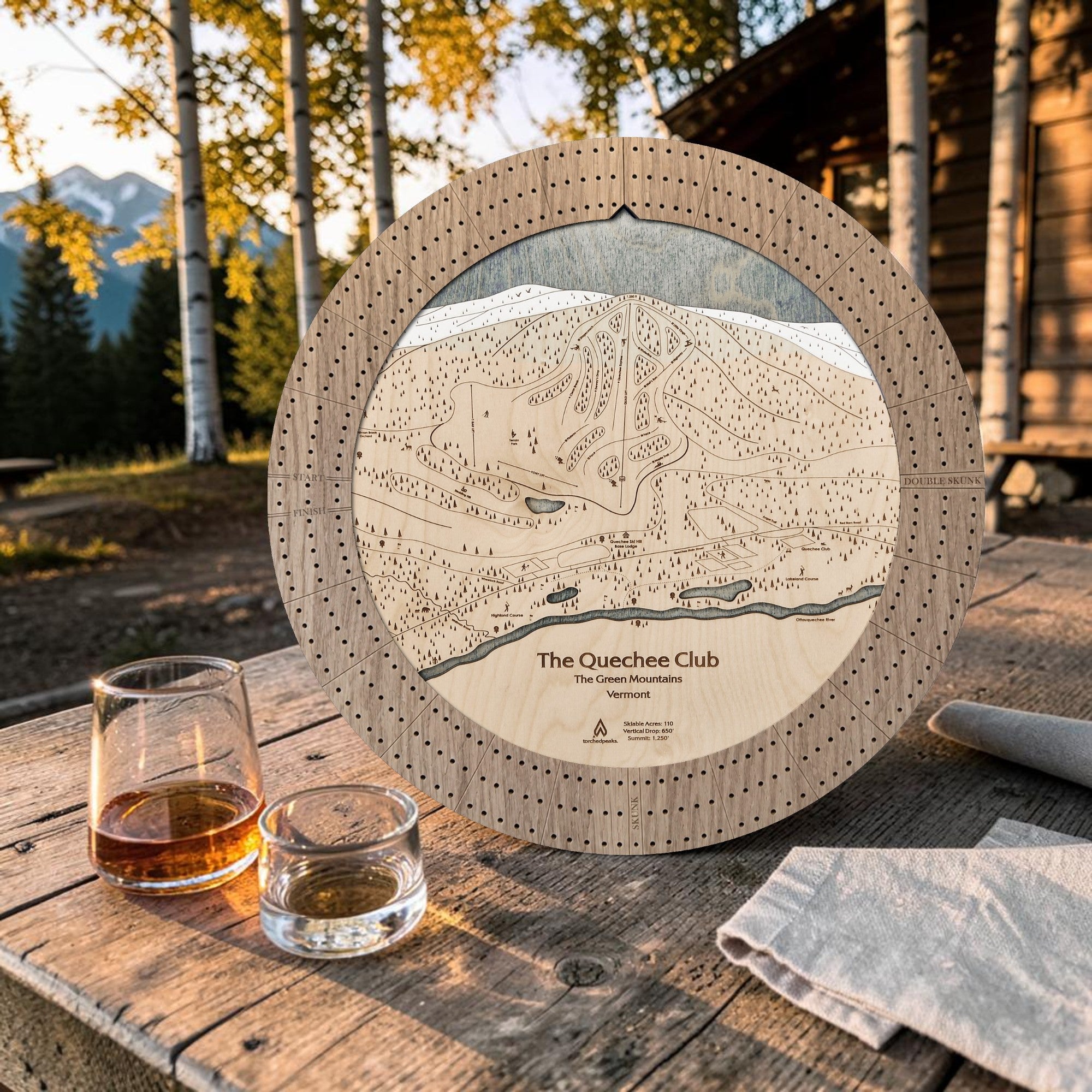 Weathered Timber Quechee Club ski map cribbage board outdoors with whiskey glasses and cards for après-ski game night.