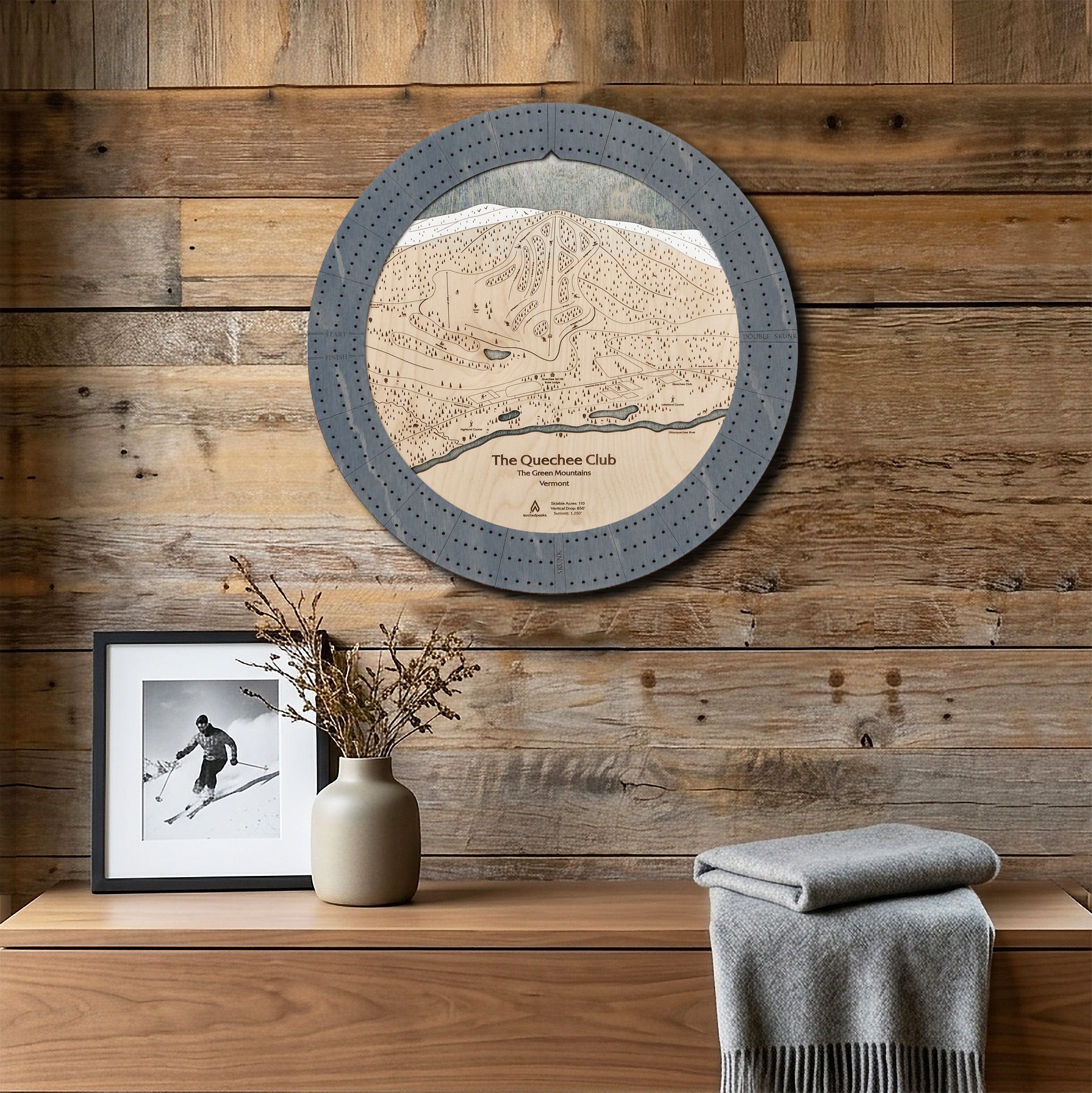 Round Quechee Club ski trail map cribbage board mounted on a reclaimed-wood wall as a handcrafted gift for skiers.