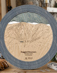 Ragged Mountain ski trail map cribbage board in Graphite Grey styled on a rustic table inside a ski cabin. 