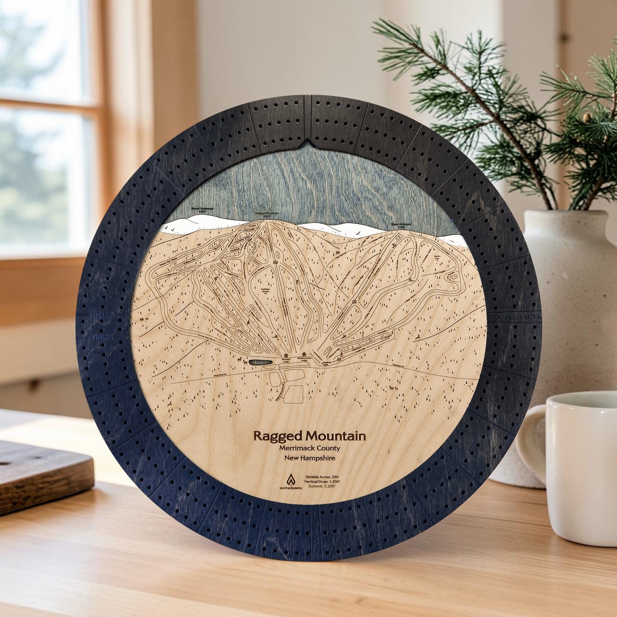 Ragged Mountain wooden cribbage board in Matte Onyx displayed near a sunlit window inside a mountain ski home.