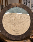 Ragged Mountain ski map cribbage board in Rustic Mocha styled on a distressed table with playing cards inside rustic ski cabin. 