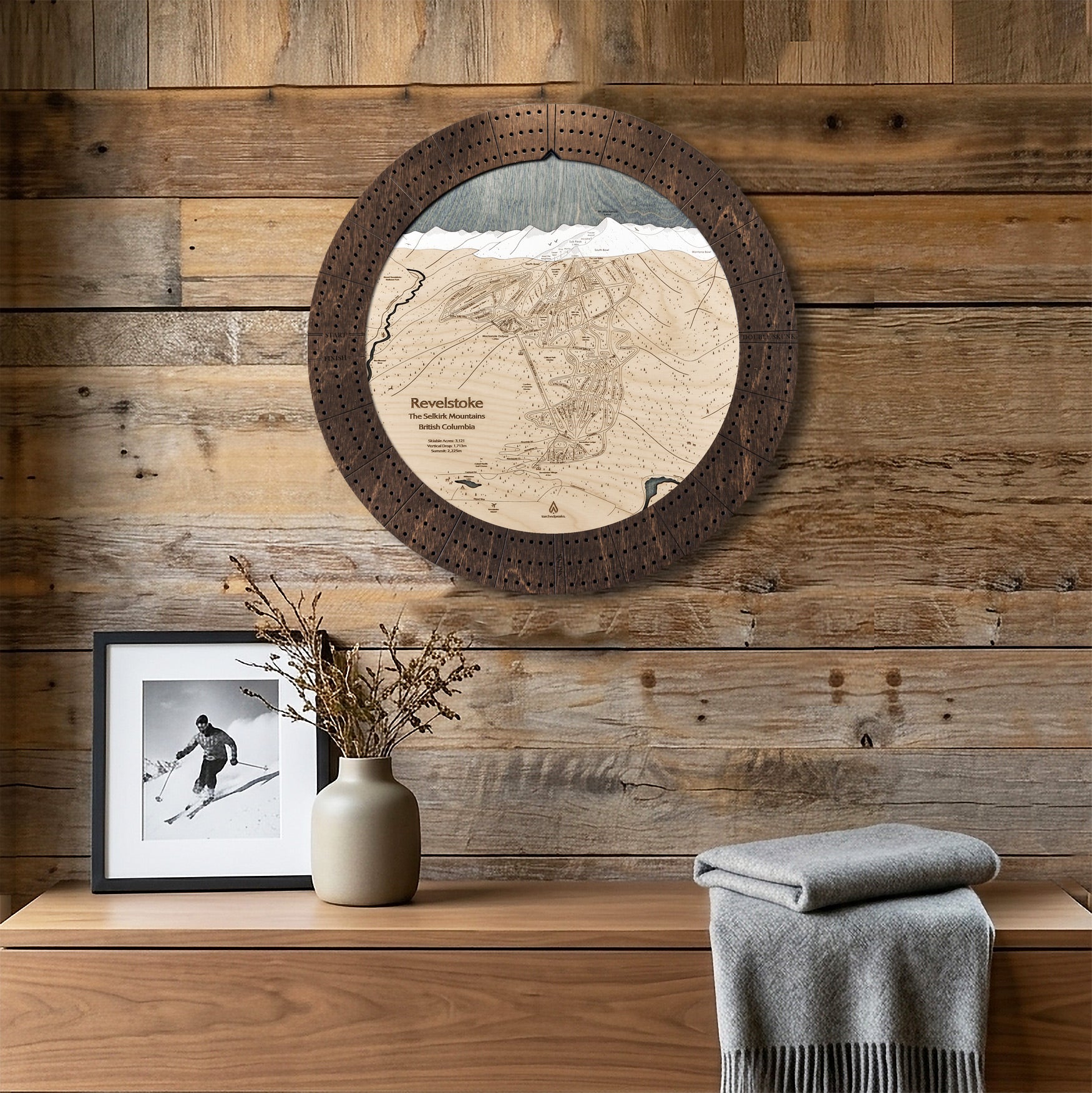Round Revelstoke ski map cribbage board mounted on a reclaimed-wood wall as distinctive ski cabin decor.